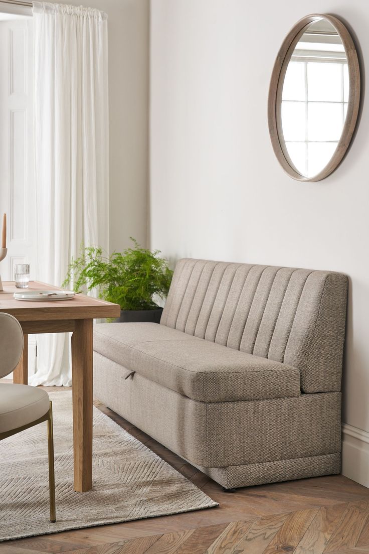 a living room with a couch, table and mirror on the wall next to it