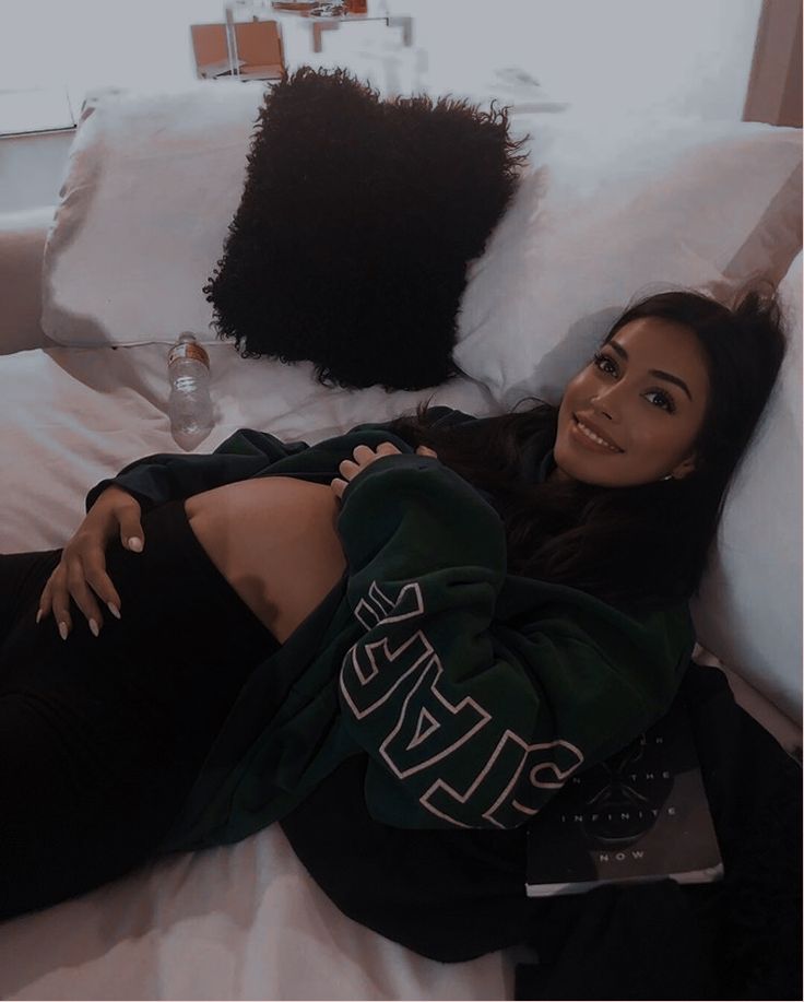 a woman laying on top of a bed next to pillows