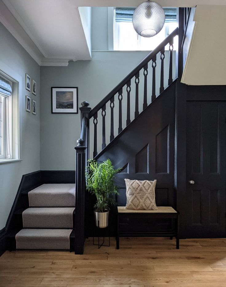 a stair case next to a set of stairs with a plant on the bench in front of it