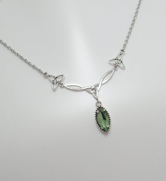 This is a new handmade necklace. It is made with antiqued silver plated Celtic knots, accented with a high quality LIGHT PERIDOT GREEN glass jewel that sparkles like crystal. Decorated portion is 2 1/2" wide and 1 1/4" tall in the center. Necklace is adjustable 15-18" with a lobster clasp and chain extender. If you would like a different length, please send us a message.Matching earrings and headpiece are listed in our store in a variety of stone colors. If you don't see items with a color you w Elven Jewelry Earrings, Silver Green Necklace, Peridot Necklace Silver, Celtic Inspired Outfits, Silver And Green Necklace, Silver And Green Jewelry, Green Wedding Necklace, Elvish Necklace, Sage Green Necklace