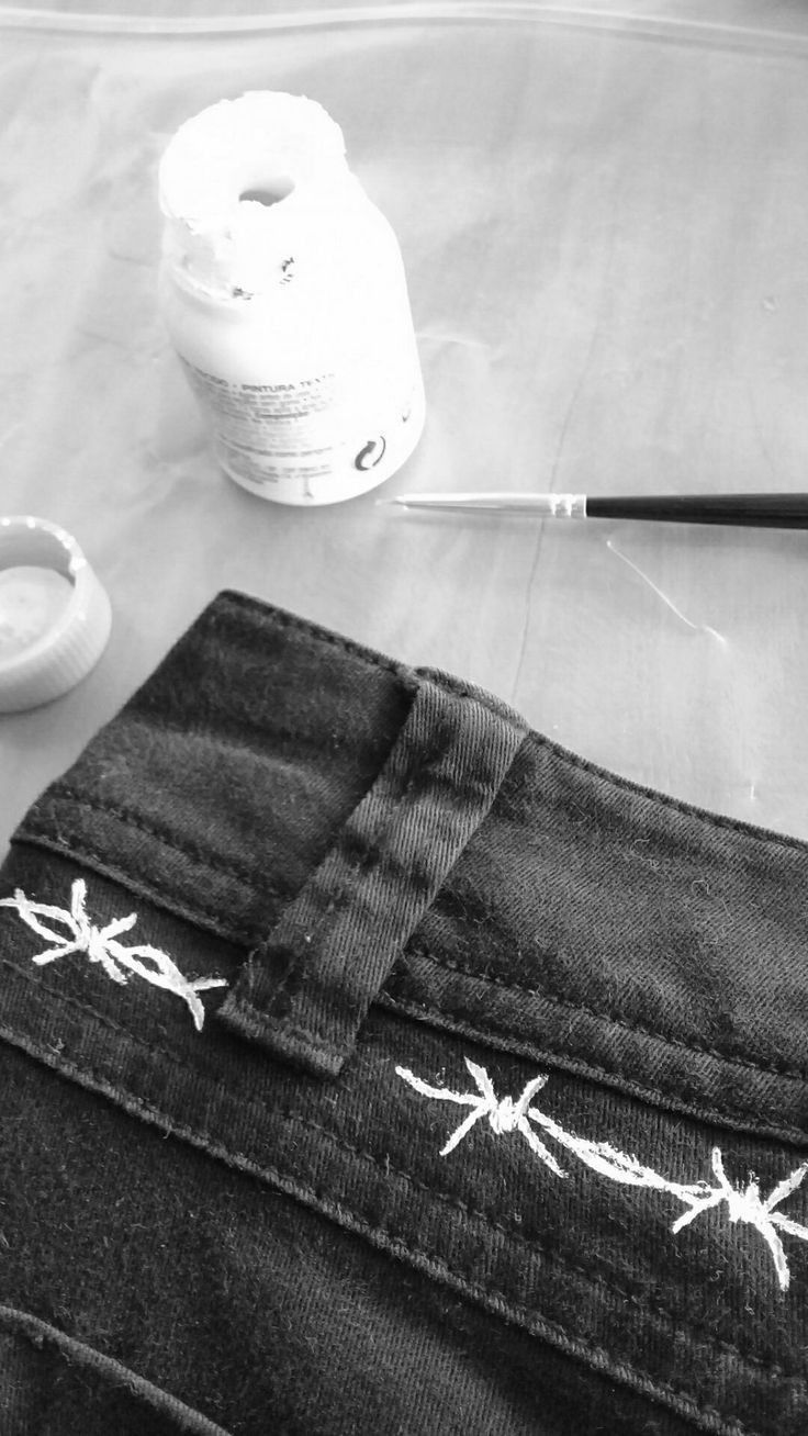 a pair of jeans with barbed wire drawn on them and a paintbrush next to it