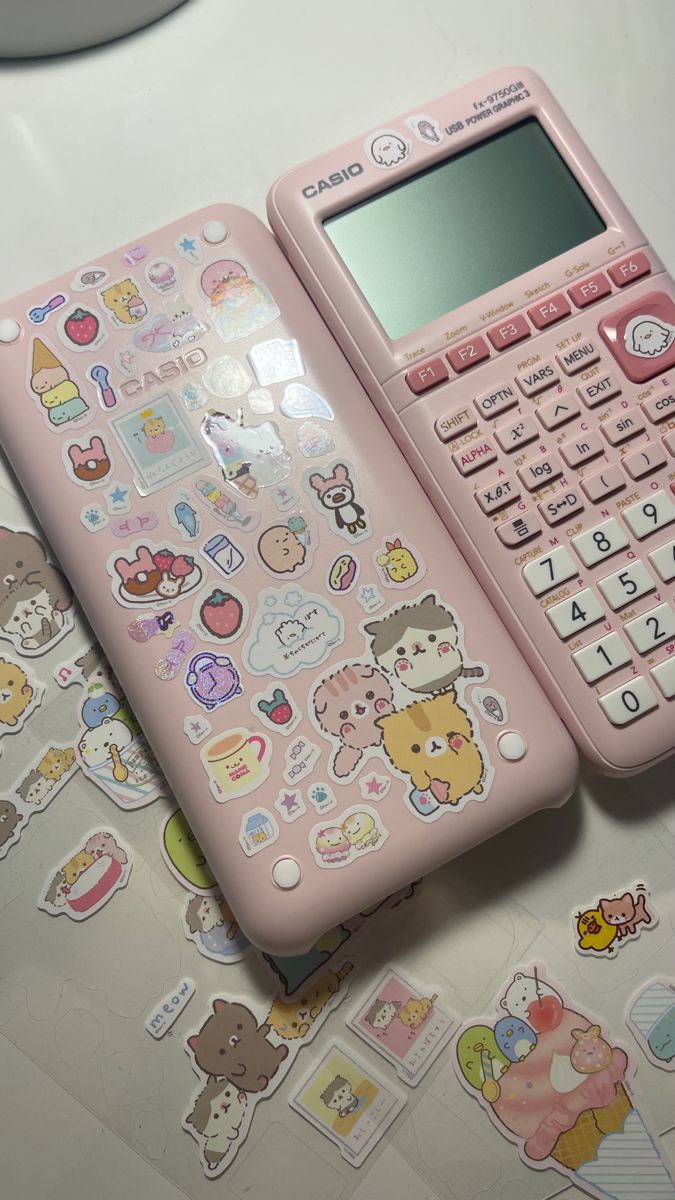 a pink calculator sitting on top of a table covered in stickers and decals