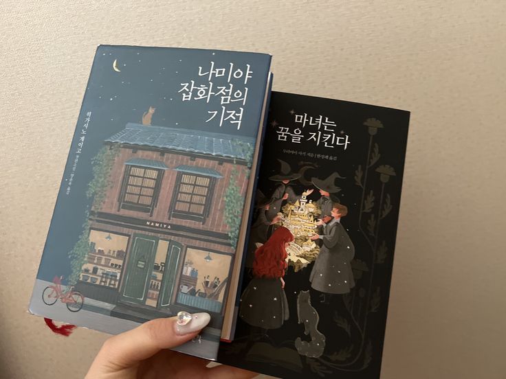 a person holding two books in their hands with an image of a house on the cover