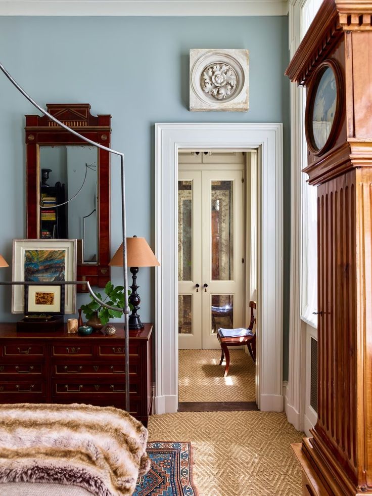 a bedroom with a bed, dresser and clock on the wall next to an entry way