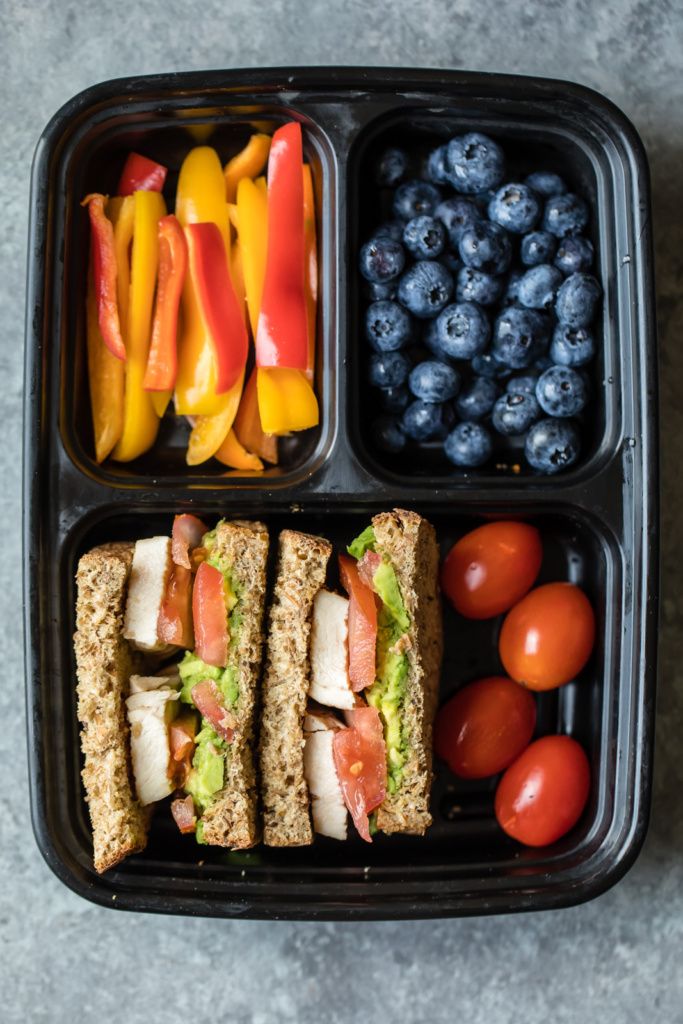 a plastic container filled with different types of food next to blueberries and oranges