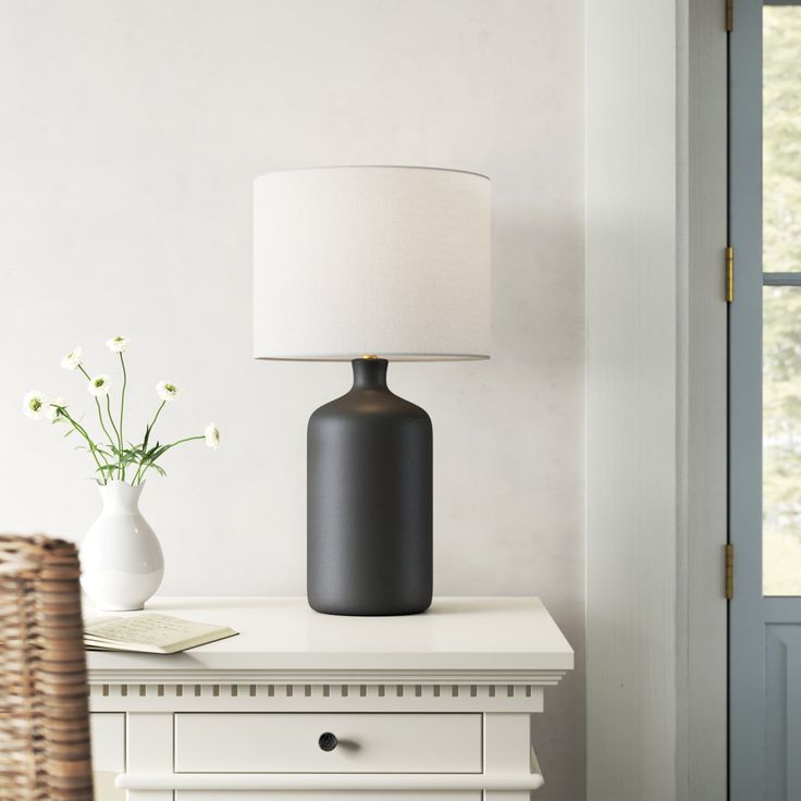 a table with a lamp, vase and basket on it next to a door way