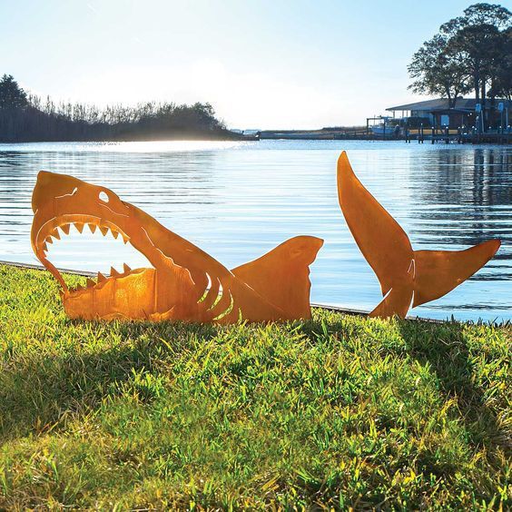 two metal shark sculptures sitting in the grass