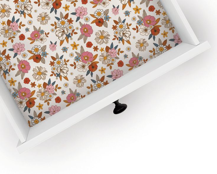 an open drawer with a flower print on the bottom and black knobs at the bottom