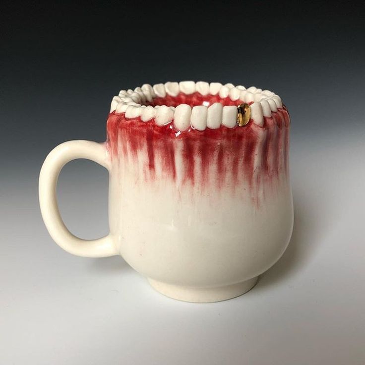 a white and red coffee cup with teeth on it