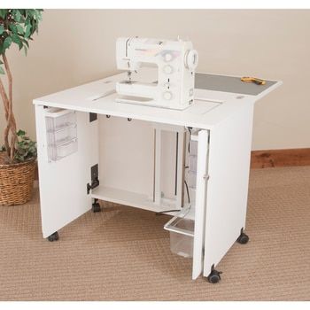 a sewing machine sitting on top of a white cabinet next to a potted plant