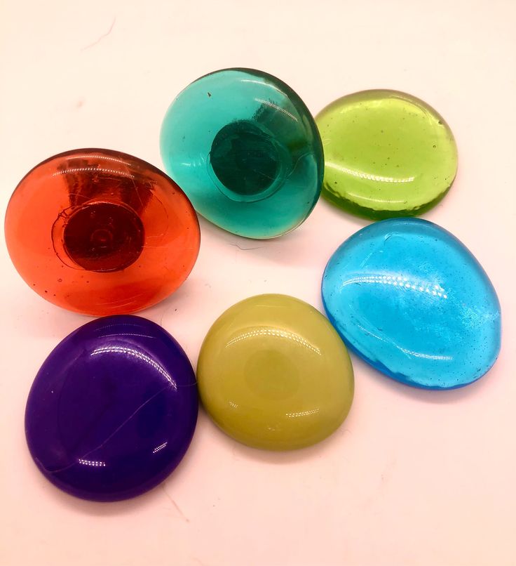 five different colored glass objects on a white surface