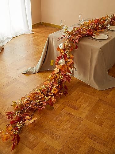 the table is set with plates and silverware on it, along with fall leaves