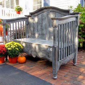 a wooden bench sitting on top of a brick walkway next to potted plants and pumpkins