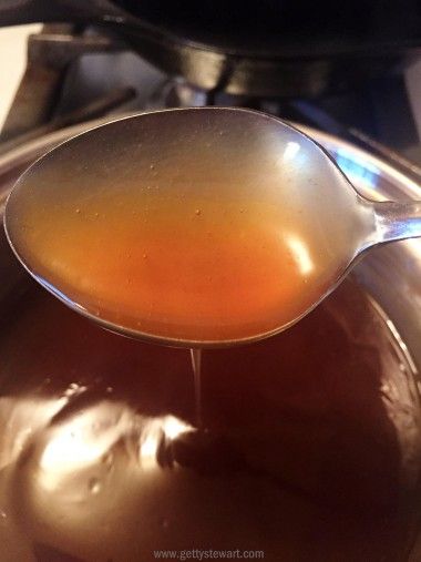 a spoon full of liquid sitting on top of a pot