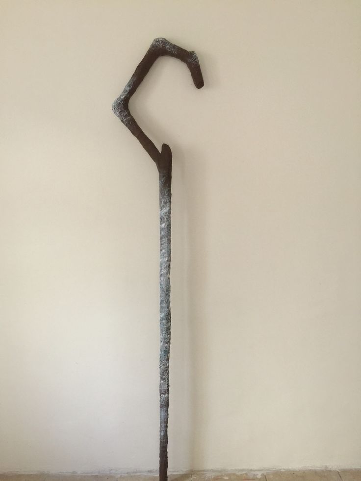 a metal pole with a long stick sticking out of it's side against a wall