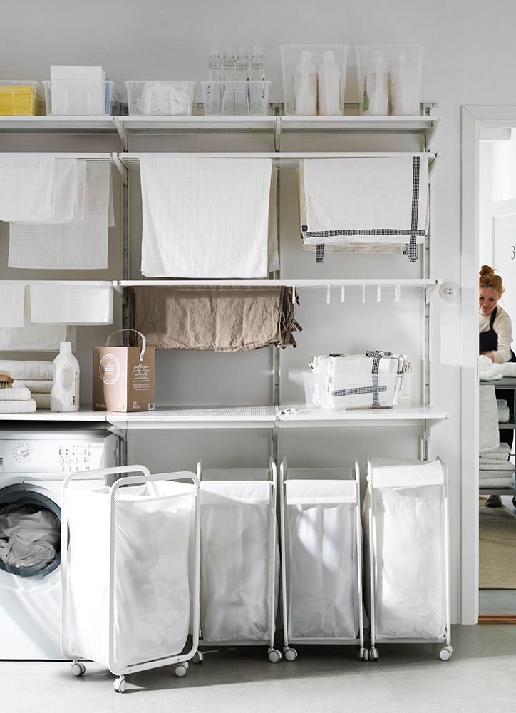 a woman standing in front of a washer and dryer next to laundry bags