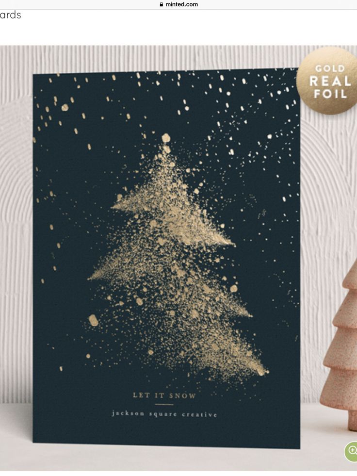 a christmas card with gold glitter on it and a small tree in the corner next to it