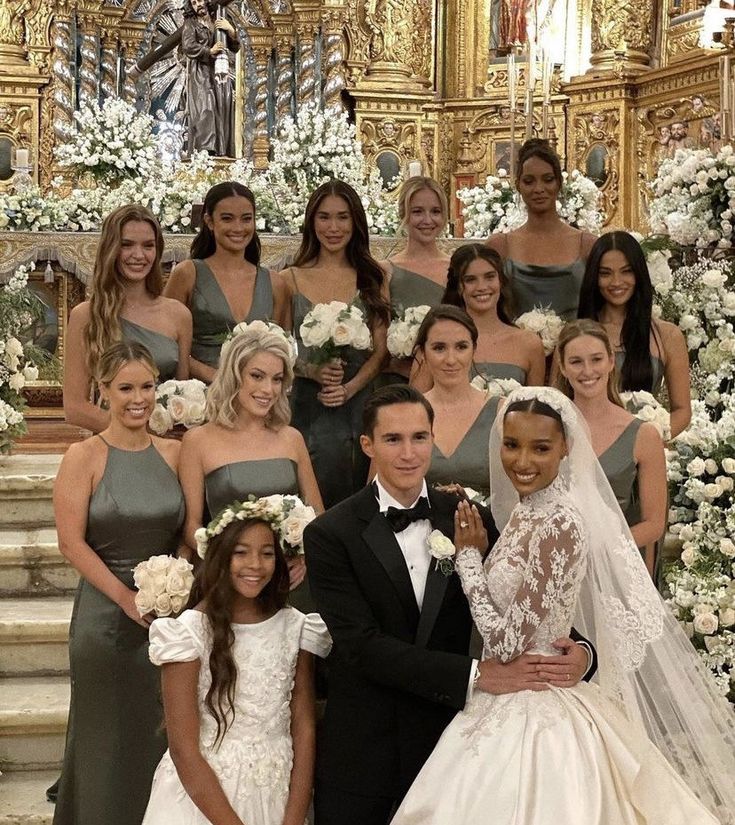 the bride and groom are posing with their bridal party in front of an ornate staircase