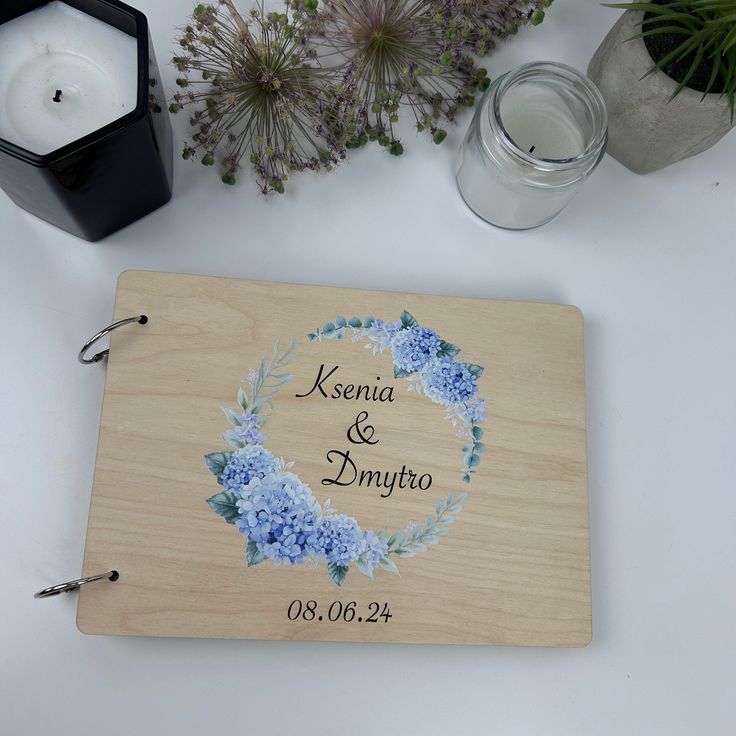 a wooden plaque with blue flowers on it next to some candles and other items that include a candle holder