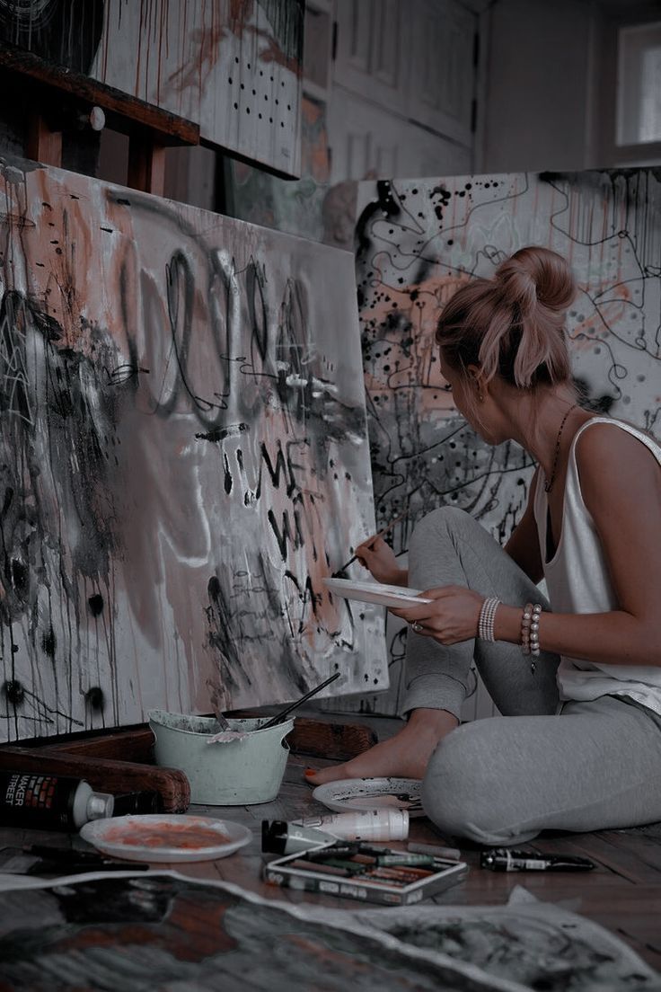 a woman is sitting on the floor painting