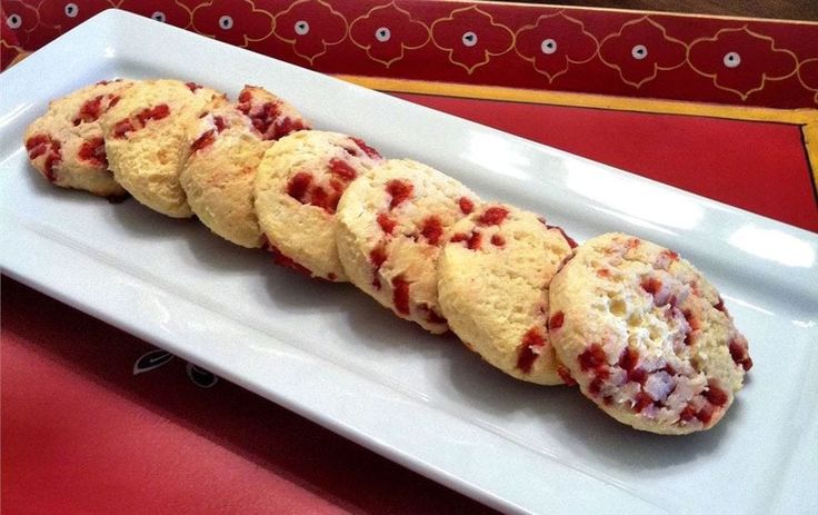 a white plate topped with cookies covered in red toppings on top of a table