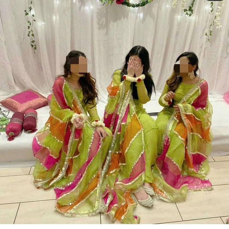 two women dressed in green and pink sitting on the floor