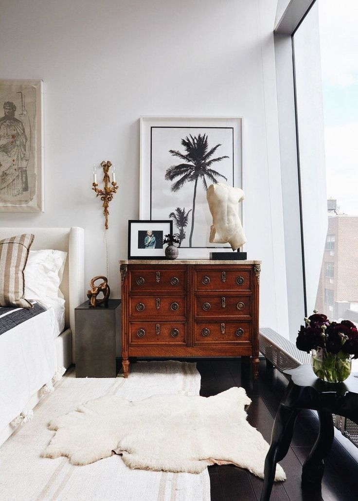 a bedroom with a bed, dresser and pictures hanging on the wall next to it