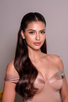 a woman with long brown hair wearing a tan dress