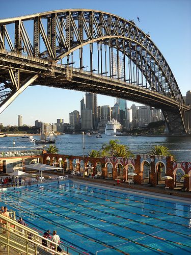 an olympic swimming pool with the sydney harbour bridge in the background