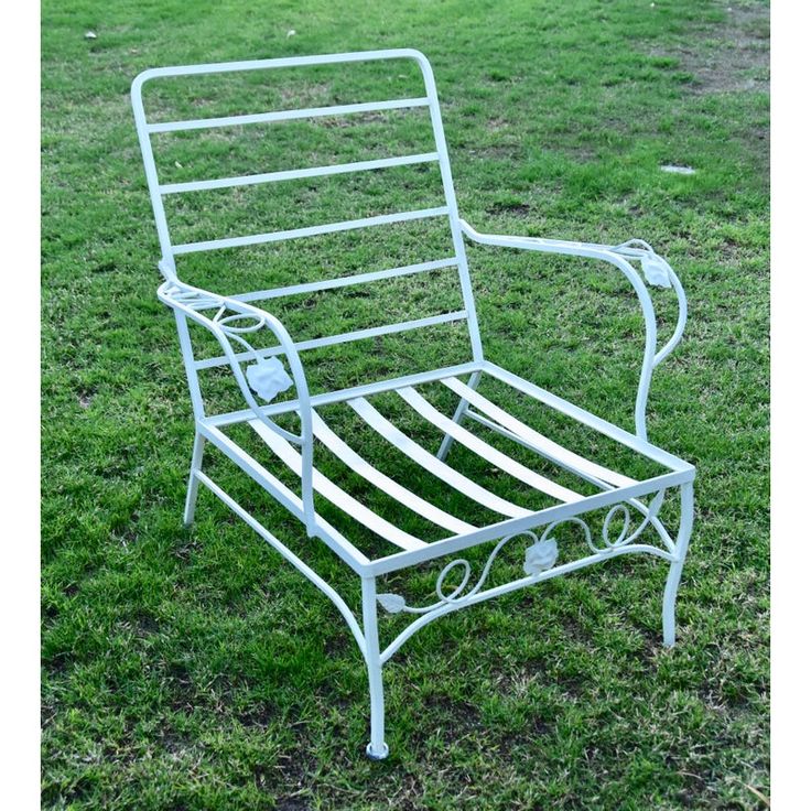 a white metal chair sitting on top of a lush green field