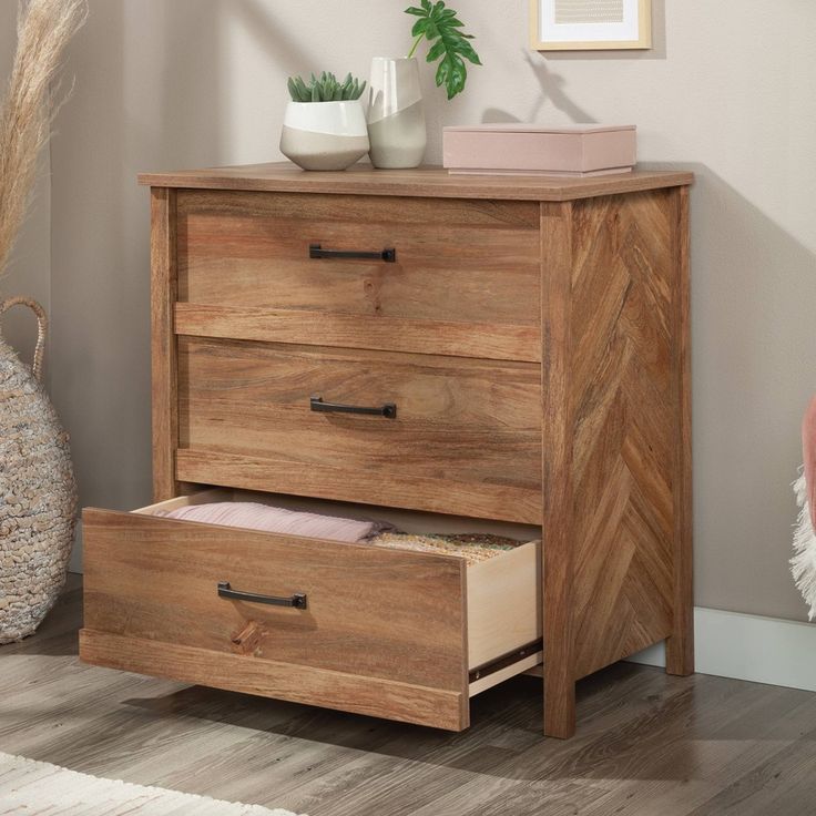 a wooden dresser with two drawers and a plant on the top shelf next to it