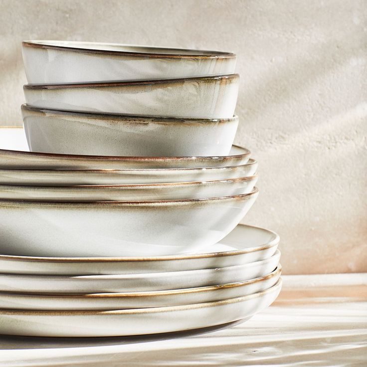 a stack of white plates stacked on top of each other in front of a wall