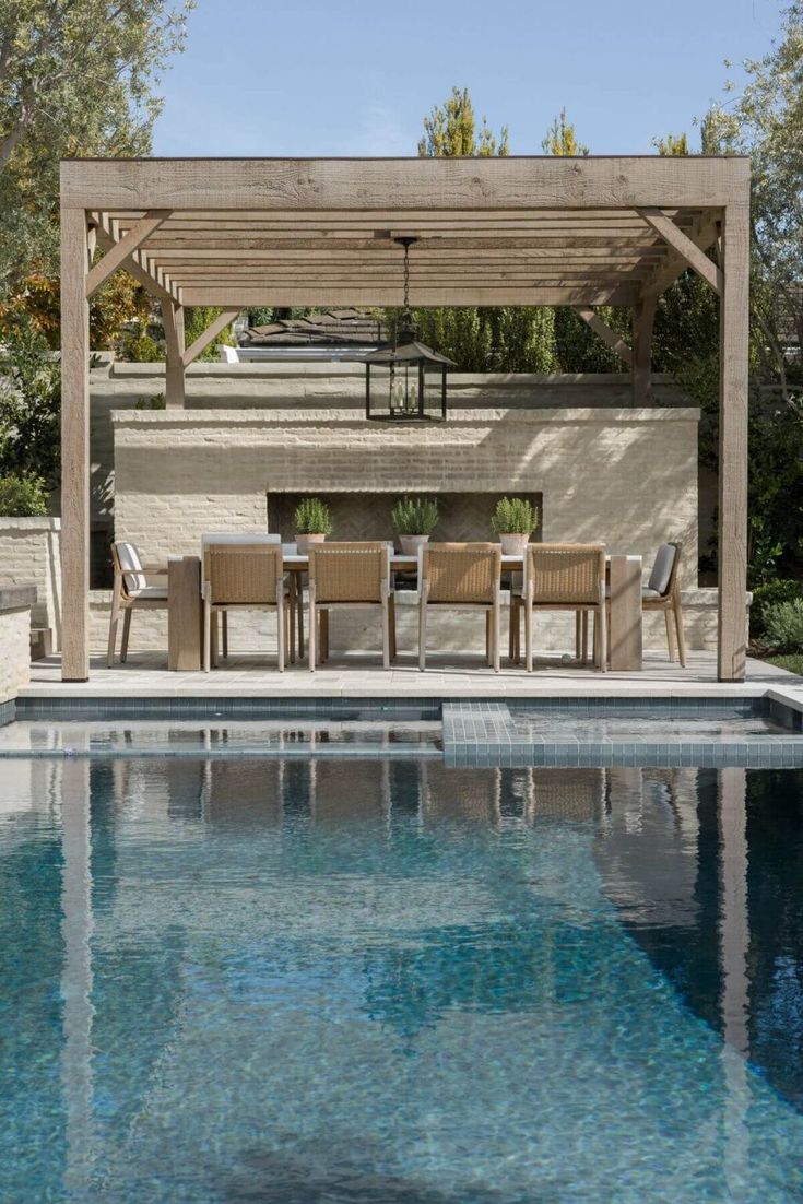 an outdoor dining area next to a swimming pool with chairs and tables on the side