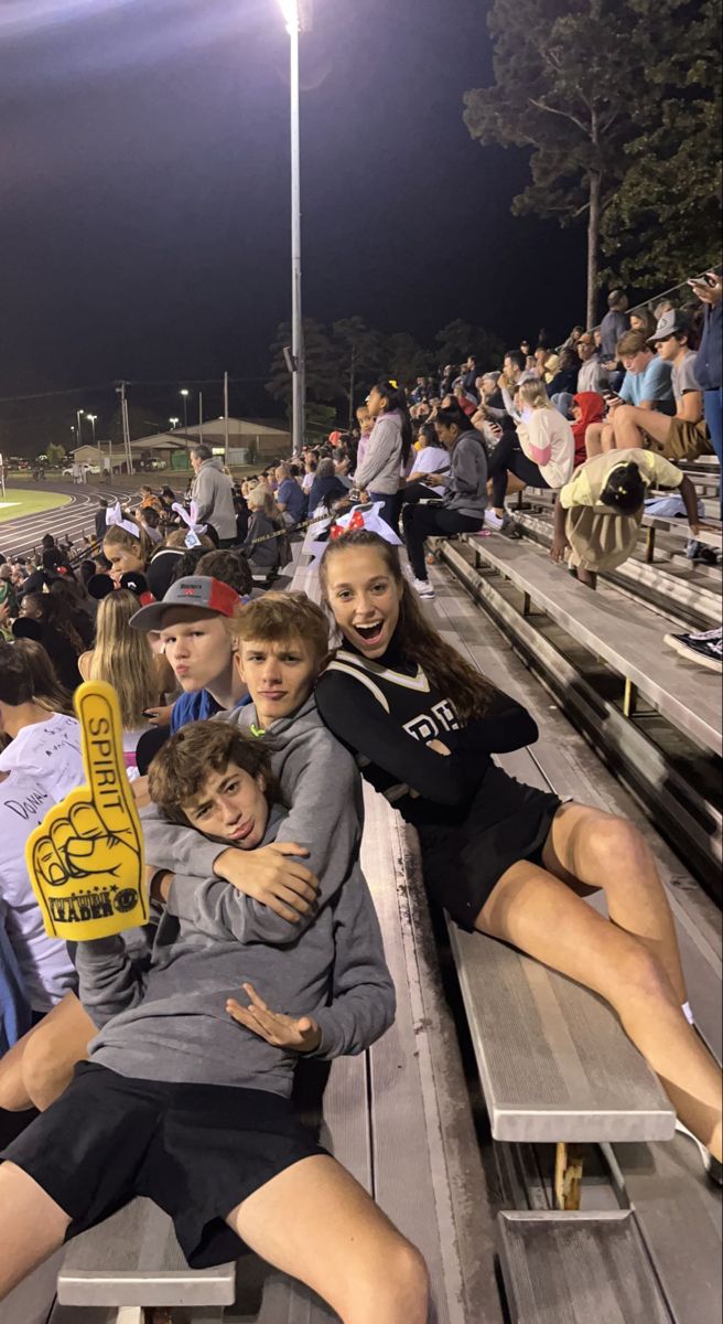 a group of young people sitting on top of wooden benches at a soccer game in front of an audience