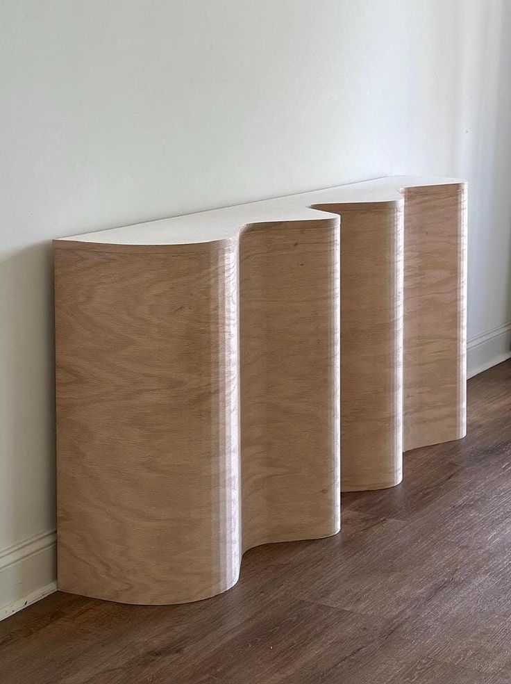 three wooden vases sitting on top of a hard wood floor next to a white wall