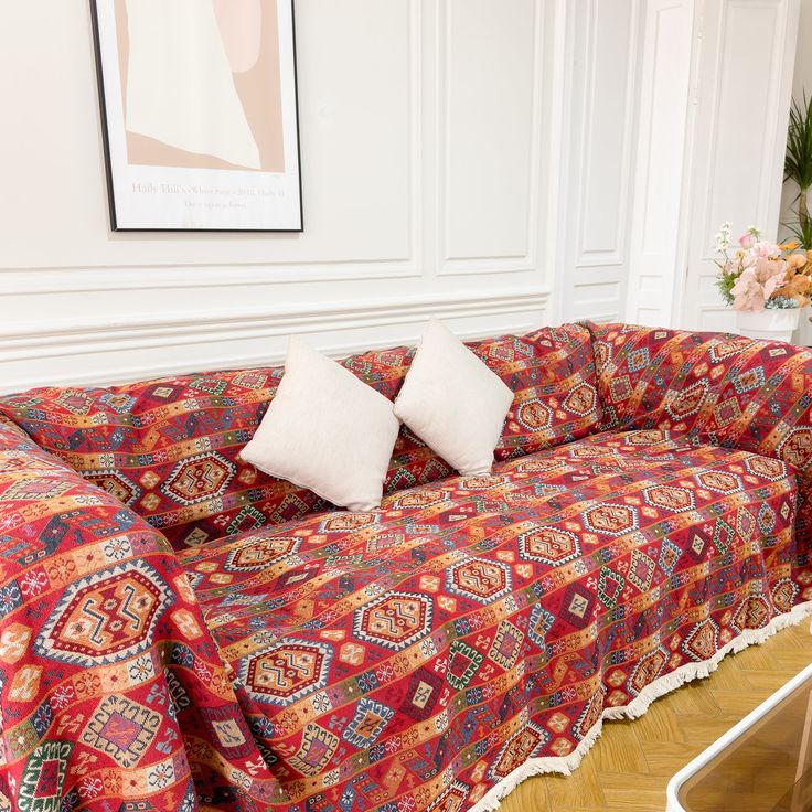 a living room with a couch covered in a colorful blanket and two white pillows on top of it