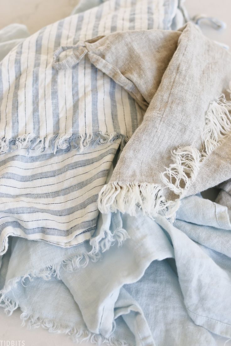 an unmade bed with blue and white striped blankets on top of eachother