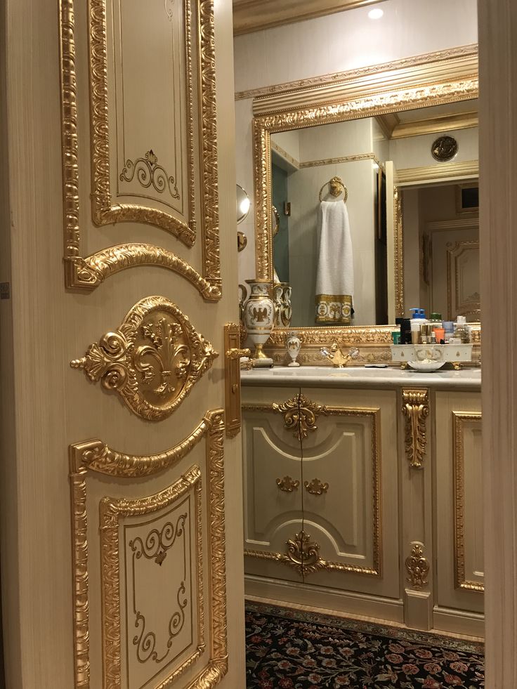 an ornately decorated bathroom door is open to reveal the sink and mirror in the room