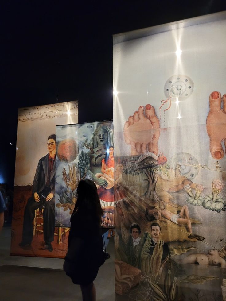 a woman standing in front of two large posters with images of people and animals on them