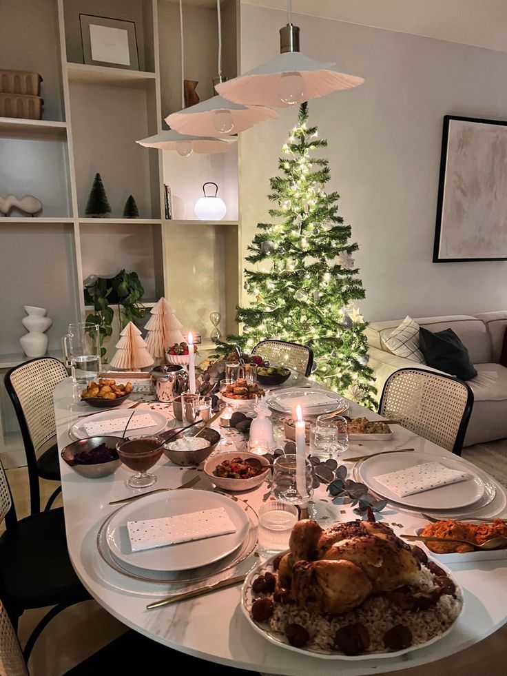 a christmas tree is in the background behind a table set with food and wine glasses