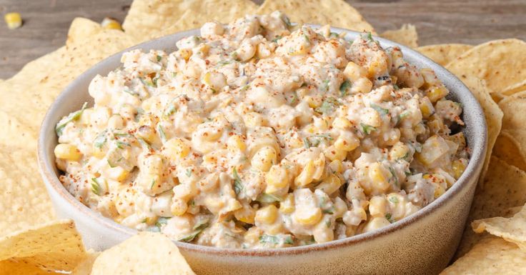 a bowl filled with corn salad surrounded by tortilla chips