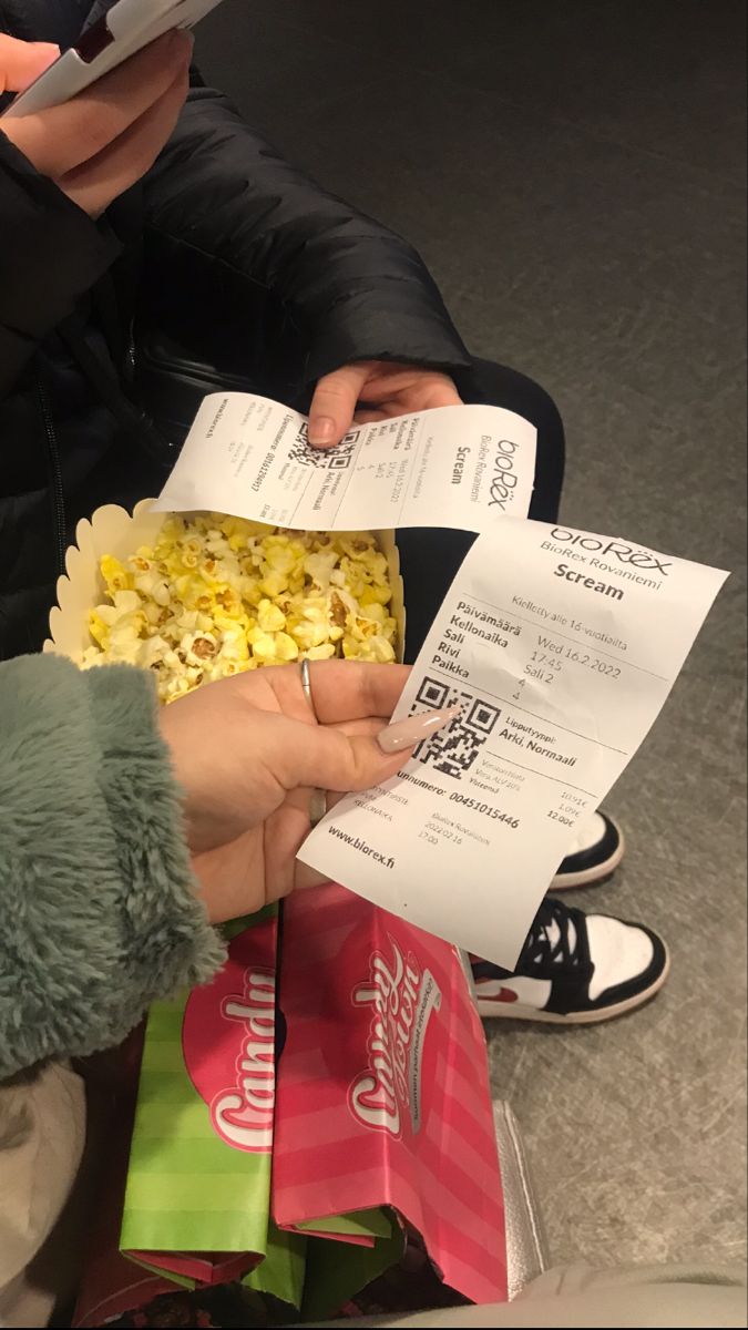 two people are sitting on the floor and one person is holding a box of popcorn