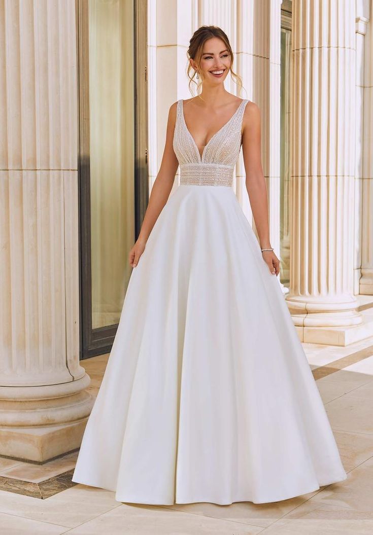 a woman standing in front of columns wearing a wedding dress