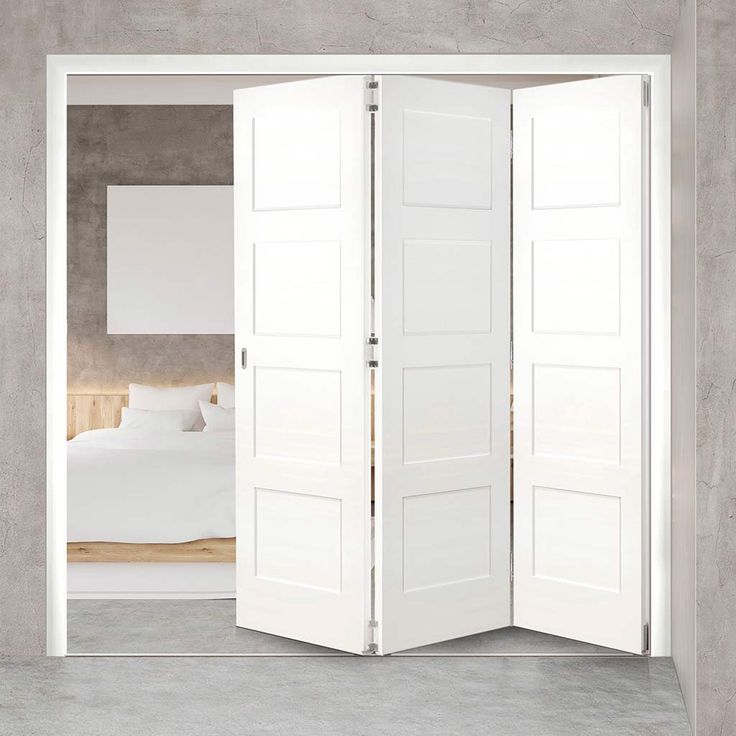 an open white door leading to a bed in a room with concrete walls and flooring