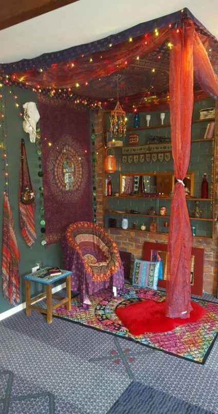 a living room decorated with red curtains and lights on the ceiling, rugs in front of bookshelves