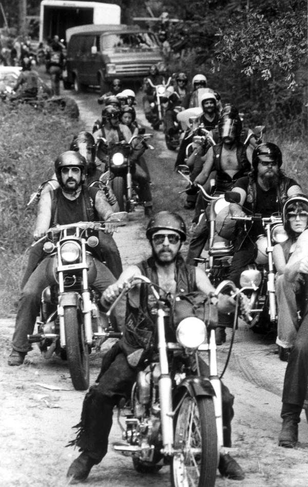 a group of men riding motorcycles down a dirt road