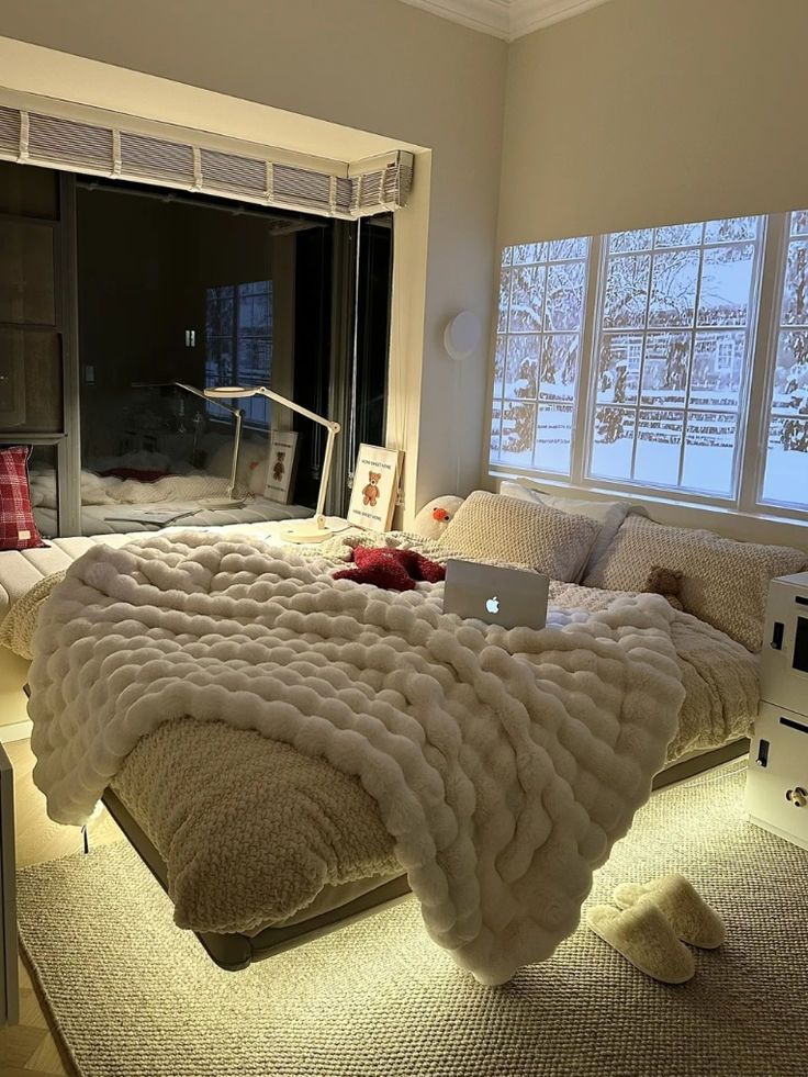 a laptop computer sitting on top of a bed in a room filled with pillows and blankets