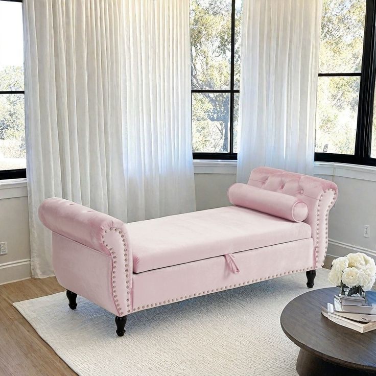 a pink chaise lounger sitting in front of a window with white drapes