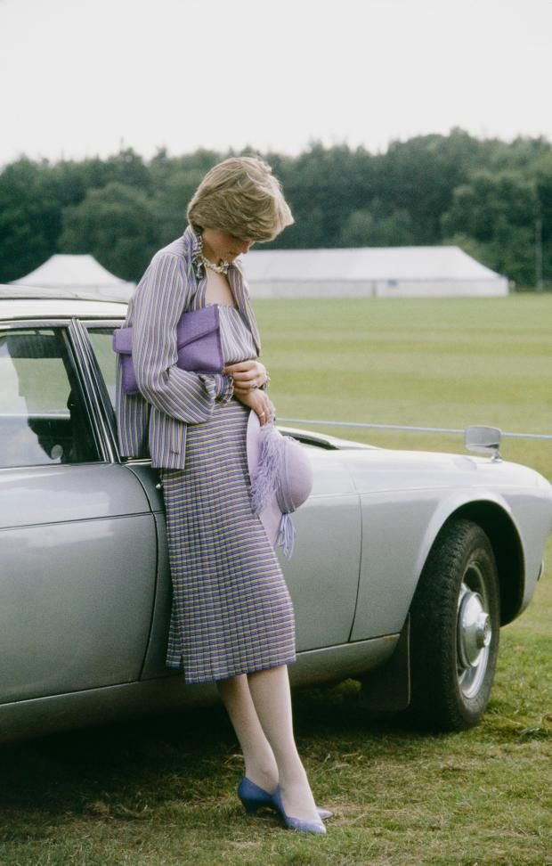 a woman leaning on the hood of a car