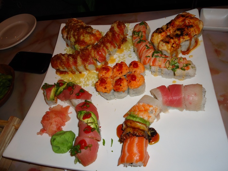 there are many different types of sushi on the white platter, including shrimp